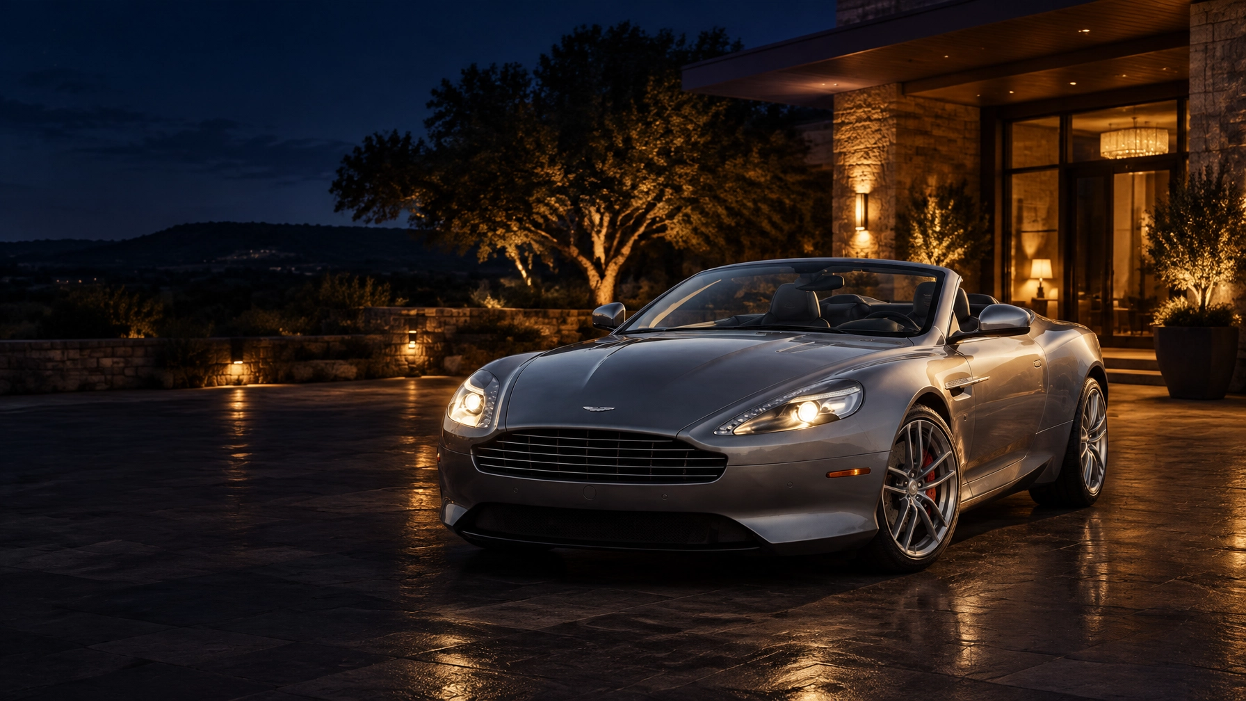 Silver-grey Aston Martin DB9 Volante parked outside a luxury Hill Country hotel at night